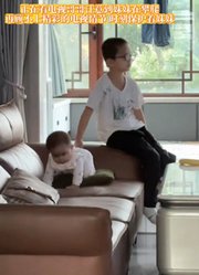 妹妹沙发上攀爬，哥哥顾不上电视的精彩，保护妹妹不让她受伤