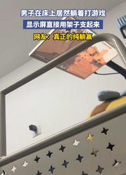 男子在床上居然躺着打游戏，显示屏直接用架子支起来