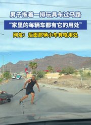 男子拖着一排玩具车过马路，“家里的每辆车都有它的用处”
