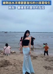 女子正在海边拍照，被刚出水冻得瑟瑟发抖的小孩哥吸引。